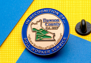 Dawson County poll worker service lapel pin with blue outer ring and gold county outline on a yellow and blue background.