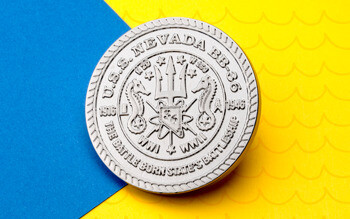 Silver challenge coin commemorating the U.S.S. Nevada BB-36, featuring a trident and seahorses on a blue and yellow background.