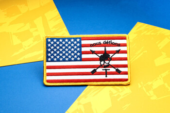 Embroidered American flag patch featuring the Nous Défions skull and crossed arrows insignia with a yellow border.